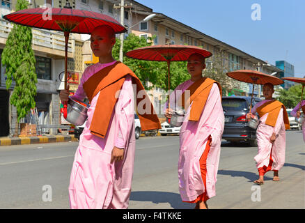 Monache noviziane che camminano lungo una strada principale che raccoglie per elemosine, Mandalay, Myanmar, ex Birmania, Sud-est asiatico Foto Stock