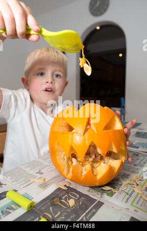 Ragazzo (di età compresa tra i 5) preparare la sua zucca di Halloween pronti per la festa di Halloween, REGNO UNITO Foto Stock