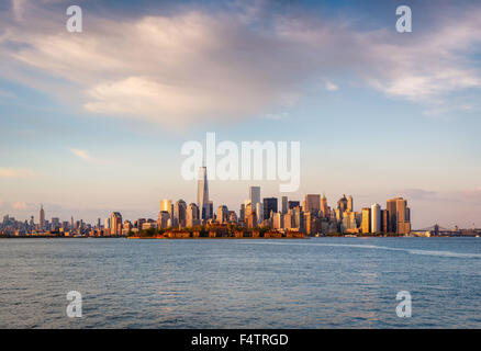New York grattacieli e il quartiere finanziario di Lower Manhattan nella luce del tramonto con Battery Park ed Ellis Island. La città di New York Foto Stock