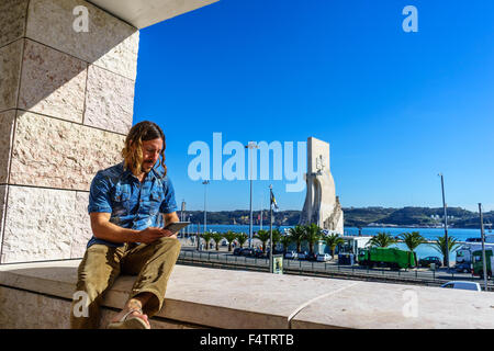 Uomo di legge da una tavoletta elettronica di fronte all'icona portoghese, Monumento alle Scoperte Padrao dos Descobrimentos. Foto Stock