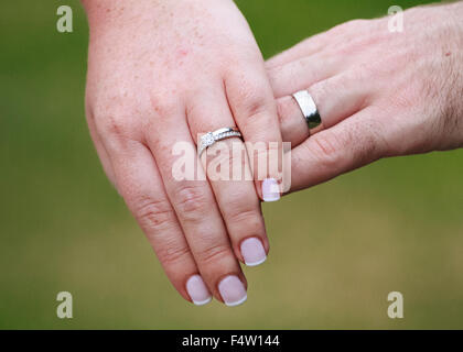 Close-up mani degli sposi mostrando loro gli anelli di nozze Foto Stock