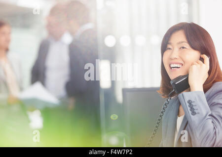 Sorridente imprenditrice parlando al telefono in ufficio Foto Stock