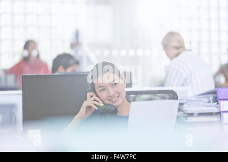 Sorridente imprenditrice parlando al telefono in ufficio Foto Stock