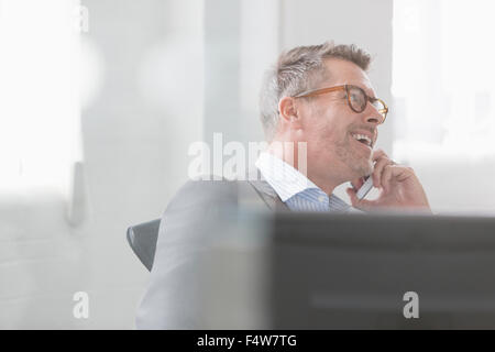 Imprenditore sorridente parlando al cellulare Foto Stock