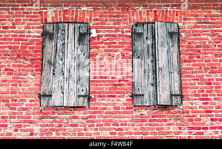 Finestre con cornici di legno rosso sul muro di mattoni. Foto Stock