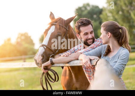 Coppia con cavallo parlava a pascolo rurale recinzione Foto Stock