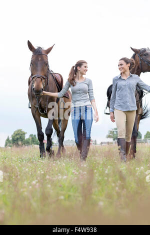 Le donne a piedi i cavalli in campo rurale Foto Stock