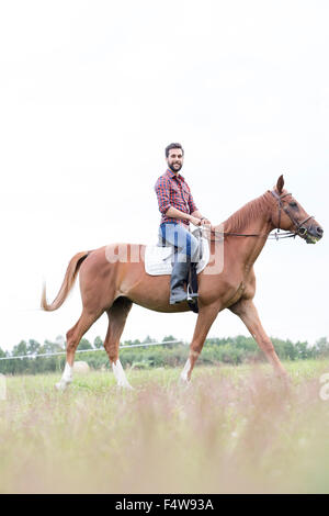 Ritratto uomo sorridente a cavallo in campo rurale Foto Stock