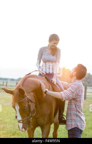 Coppia sorridente a cavallo in pascolo rurale Foto Stock