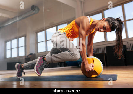 Montare facendo femmina nucleo di intenso allenamento in palestra. Giovane donna muscolare facendo esercizio di nucleo sul tappetino fitness nel club salute. Foto Stock