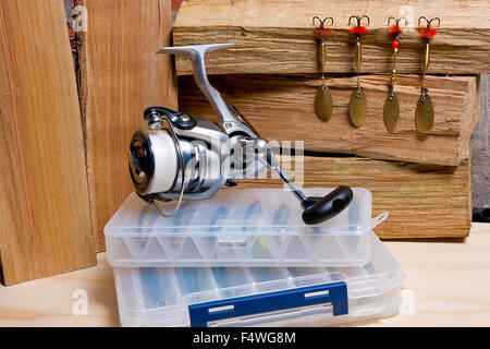 Mulinello da pesca con esche di metallo su sfondo di legno. Punte diverse della maschera di pesca di esche. Foto Stock