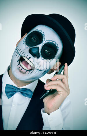 Ritratto di un uomo messicano con calaveras trucco, indossando il filtro bow tie e top hat sul telefono Foto Stock