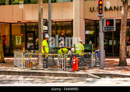 Operai di colore giallo luminoso canottiere e duro cappelli a lavorare nel centro città di Portland Oregon Foto Stock