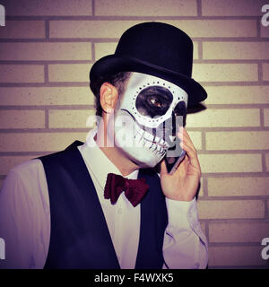 Ritratto di un uomo messicano con calaveras trucco, indossando il filtro bow tie e top hat sul telefono Foto Stock