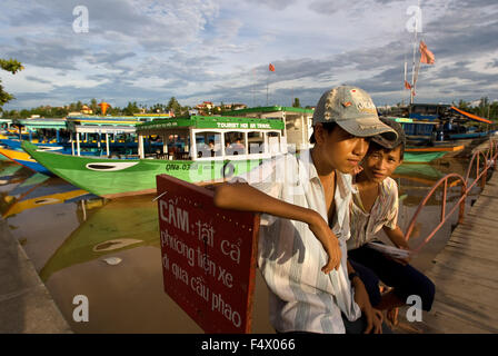 Barche tradizionali sulla canzone Thu Bon river, Hoi An, Vietnam, sud-est asiatico. I bambini di fronte al molo. Hoi An, Vietnam. Foto Stock