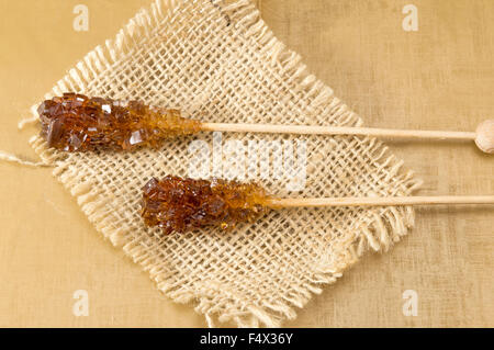 Due cristallizzato marrone bastoncini di zucchero sulla tovaglia rustico Foto Stock