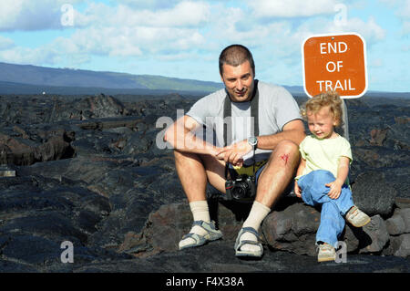 Il padre con la sua doughter alla fine del sentiero. Lava nera montagne vicino alla costa e catena di autostrada del cratere Road. Hawai'i Volc Foto Stock