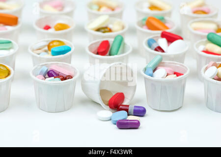 Varietà di pillole colorate disposte in carta bianca COPPETTE FARMACO. Foto Stock