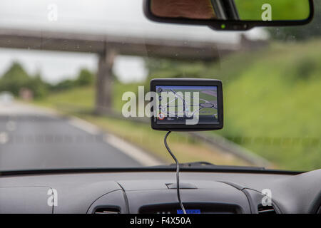 Driver maschio utilizzando un navigatore satellitare (Satellite Navigation Device) su una strada principale nel Regno Unito Foto Stock