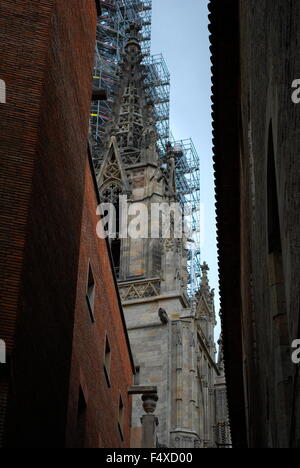 Campanile di una chiesa con un ponteggio visto da una strada stretta tra due vecchi edifici di appartamenti a Madrid. Foto Stock