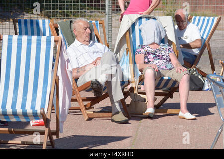 Le persone anziane sole con sedie a sdraio su hot settembre giornata a Oddicombe beach, Torquay, Devon, Inghilterra Foto Stock