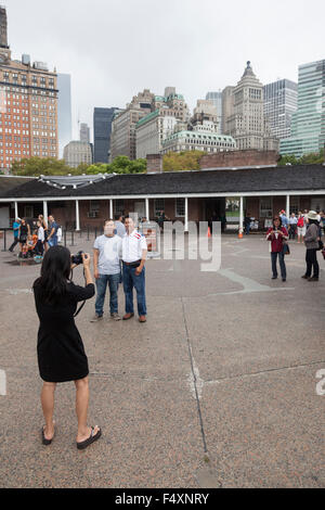 Tourist prende le immagini di persone e il centro di Manhattan in Castle Clinton nel parco della batteria Foto Stock