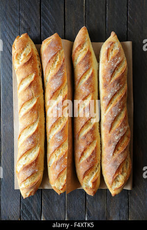 Quattro baguette francese su assi di legno Foto Stock