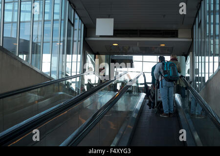 Viaggiatori in escalator dai treni di collegamento al terminale 3, zona di check-in in aeroporto di Copenhagen, CPH KASTRUP. Foto Stock