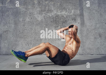 Modello di fitness esercizio sit ups e scricchiola. Muscoloso ben costruire, corpo tonico con six pack sudorazione. Spazio di copia Foto Stock