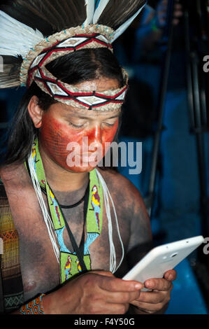 Palmas, Brasile. 23 Ott, 2015. Un Pataxo partecipante utilizza una smart phone durante la cerimonia di apertura al primo mai internazionale giochi indigeni, nella città di Palmas, stato di Tocantins, Brasile. Credit: Sue Cunningham/fotografica Alamy Live News Foto Stock