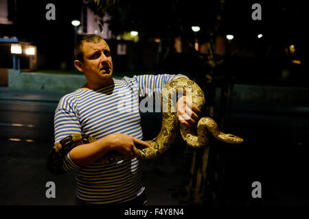 Un israeliano uomo detiene una Boa constrictor, chiamato anche red-tailed boa o il comune boa snake in Jaffa street west Jerusalem Israel Foto Stock