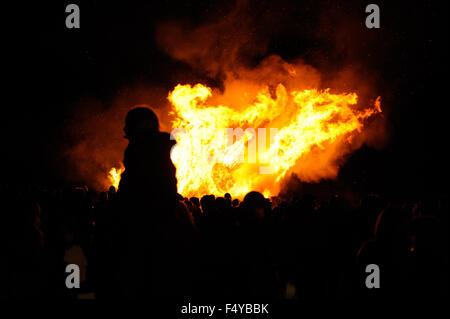 La gente si stagliano contro le fiamme di un grande falò per festeggiare Novembre 5th, noto anche come notte dei falò, nel villaggio di Firle in East Sussex, Inghilterra. Foto Stock