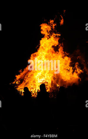 La gente si stagliano contro le fiamme di un grande falò per festeggiare Novembre 5th, noto anche come notte dei falò, nel villaggio di Firle in East Sussex, Inghilterra. Foto Stock