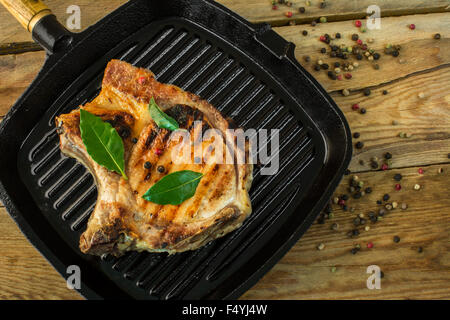 Filetto arrosto in padella per grigliare con fresche foglie di alloro e il pepe in grani su uno sfondo di legno spazio copia Foto Stock