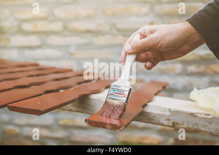 L'uomo pittura picchetti in legno per recinzione hash, dai toni rétro immagine con il fuoco selettivo Foto Stock