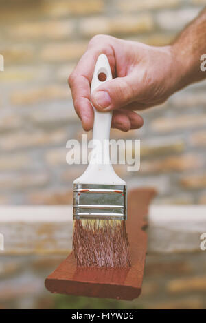 L'uomo pittura picchetti in legno per recinzione hash, dai toni rétro immagine con il fuoco selettivo Foto Stock