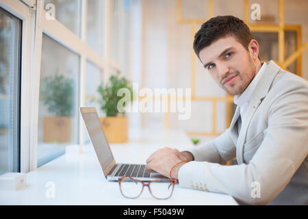 Uomo bello utilizzando computer sul posto di lavoro Foto Stock