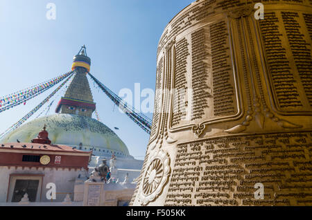 Grande campana con iscrizione in lingua tibetean con boudnath stupa in background Foto Stock