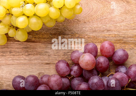 I grappoli di uve bianche e rosse su sfondo di legno Foto Stock