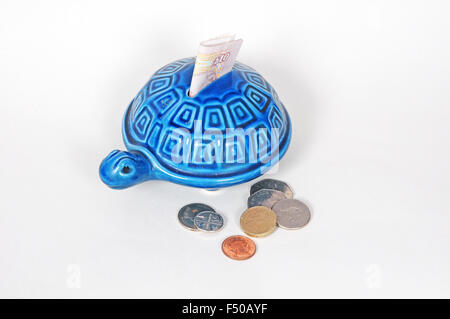 Tartaruga scatola di denaro con dieci pound nota e monete sterling Foto Stock