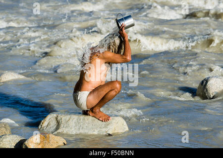Un maschio di pellegrino presso le rive del fiume Gange è prendere una doccia con l'acqua santa Foto Stock