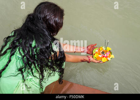 Una giovane donna con lunghi capelli neri, Henna dipinto di mani è in possesso di un Deepak, un fiore che offre, al ghats di fiume santo Foto Stock