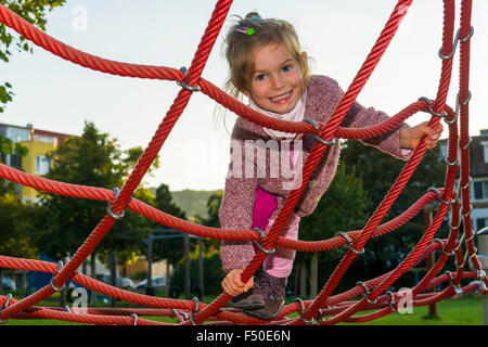 Una bambina di tre anni è la scalata di una impalcatura di corda Foto Stock