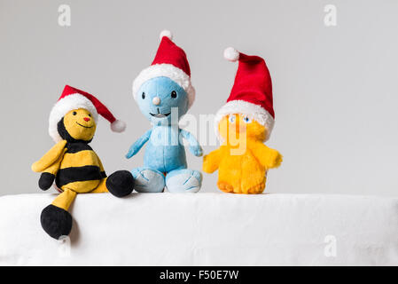 Una luce blu, un giallo nero e giallo di un giocattolo di peluche, indossando il babbo natale cappelli, sono seduti insieme su un tavolo bianco Foto Stock