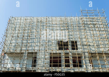 Un sito di costruzione di un nuovo edificio in cemento con una impalcatura di bamboo attaccata Foto Stock