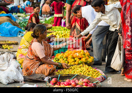 Una donna è la vendita di arance, tigli e mele al settimanale mercato vegetale Foto Stock