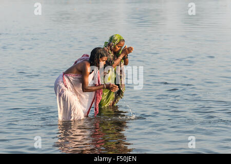 Due pellegrini femminile, le donne sono tenendo bagno e pregando nel sacro fiume Yamuna Foto Stock