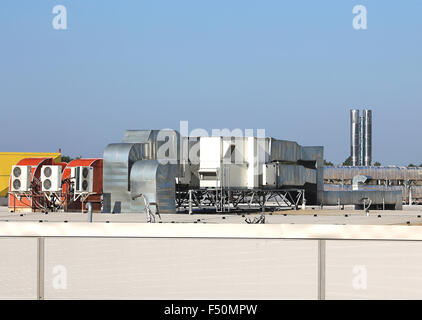 Tubi di ventilazione e gli attuatori sul tetto di un edificio industriale Foto Stock