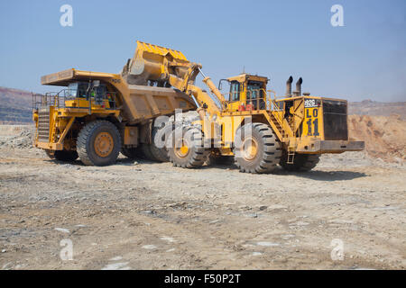 Azione girato di un caricatore frontale del riempimento di una grande-haul dump il mio carrello con terreno scavato. Settore minerario in Zambia, Africa. Foto Stock