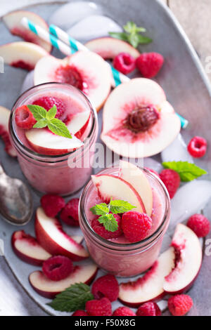 Lampone e bianco frullato di pesche in vasetti di vetro Foto Stock